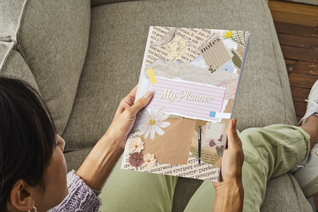 Person holding My Weekly Planner Journal with a floral collage cover while relaxing on a sofa