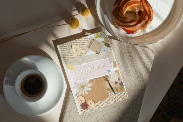 My Weekly Planner Journal cover on a desk with coffee and pastry in a cozy lifestyle setting