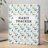 Habit tracker notebook styled on a desk with pencil, plant, and soft neutral background