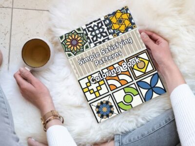 A woman relaxing with the Simple Satisfying Patterns Coloring Book and a cup of tea.